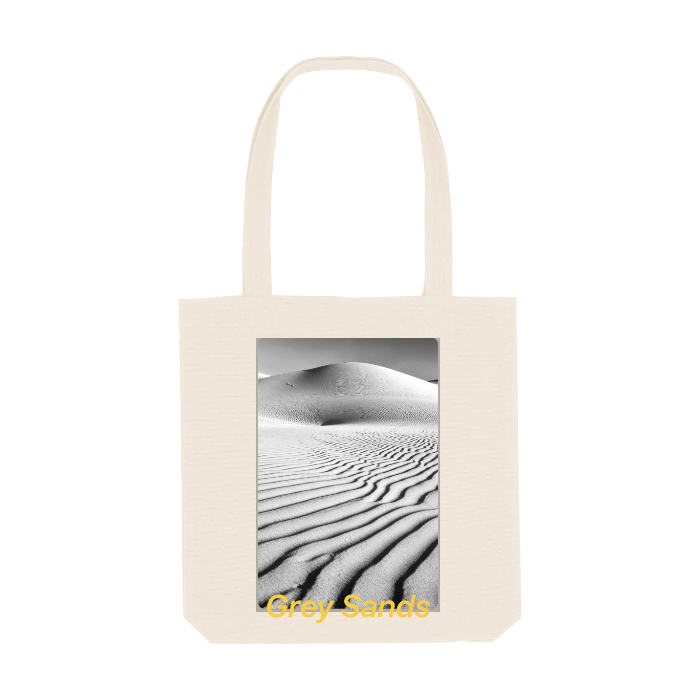 The STAU760 Stanley/Stella Organic Cotton Woven Tote Bag, by Stanley/Stella, is made from recycled materials and features a black and white desert image with sand dunes and the text "Grey Sands.