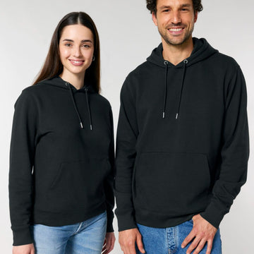 Two individuals, one in a Stanley/Stella STSU177 Stella/Stella Cruiser 2.0 The Iconic Unisex Hoodie Sweatshirt and blue jeans, and the other in a black sweatshirt and light blue jeans, stand side by side against a plain background.