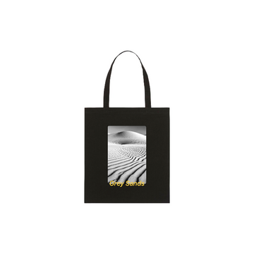 The STAU773 Stanley/Stella Organic Cotton Light Woven Tote Bag is black, featuring a desert dunes image and the text "Grey Sands" elegantly printed below.