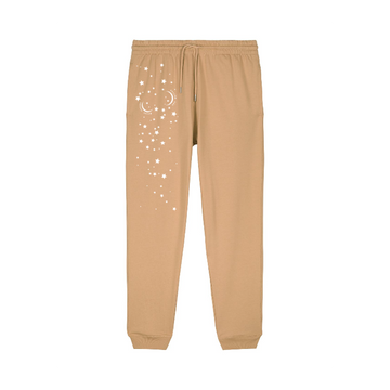 The STBU185 Stella/Stella Mover 2.0 Iconic Unisex Jogger Pants by Stanley/Stella offer comfort and style in tan organic cotton brushed fleece, with an elastic waistband and white star patterns on the left leg.