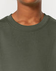 Close-up of a person wearing the dark green STSK181 Stella/Stella Mini Changer 2.0 The Iconic Kids’ Crew Neck Sweatshirt from Stanley/Stella, made from organic cotton. The photo is cropped at the shoulders and upper neck.