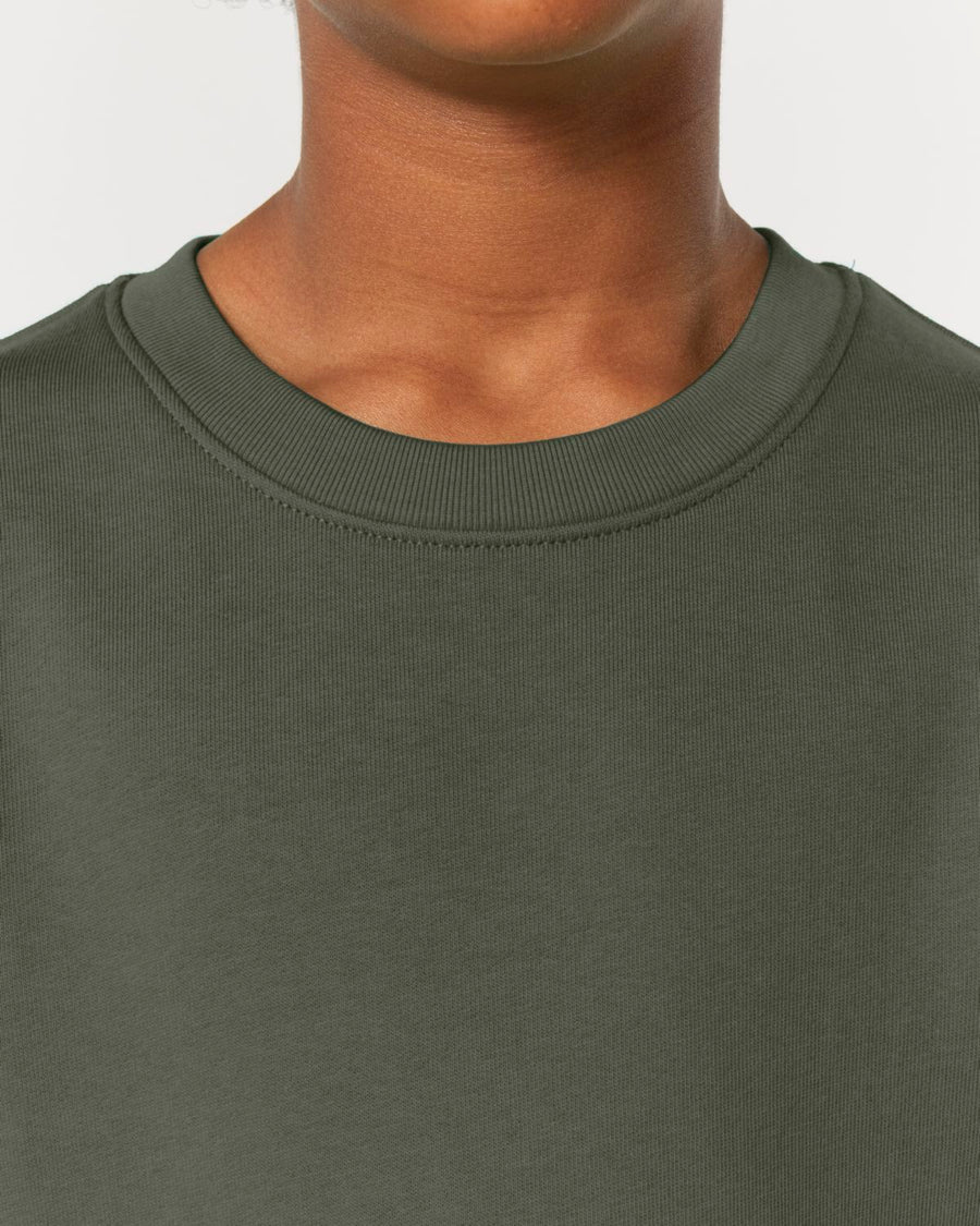 Close-up of a person wearing the dark green STSK181 Stella/Stella Mini Changer 2.0 The Iconic Kids’ Crew Neck Sweatshirt from Stanley/Stella, made from organic cotton. The photo is cropped at the shoulders and upper neck.