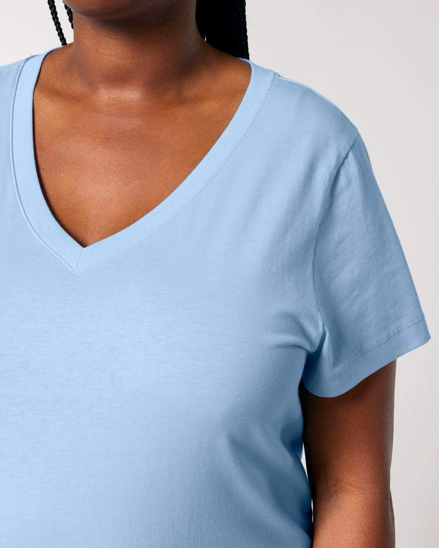 A person is wearing the STTW176 Stella Isla Women's V Neck T-Shirt from Stanley/Stella, crafted in light blue organic cotton, against a neutral background.