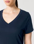 A person is shown from shoulders to chest, wearing the dark STTW176 Stella Isla Women's V-Neck T-Shirt by Stanley/Stella, made from organic cotton.