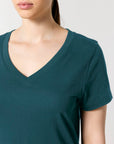 An individual wearing the STTW176 Stella Isla Women's V-Neck T-Shirt by Stanley/Stella, showcased from neck to upper chest, in green organic cotton.