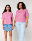 Two women wearing STTW175 Stella Nova organic cotton pink t-shirts with a boxy fit and jeans stand side by side against a neutral background.